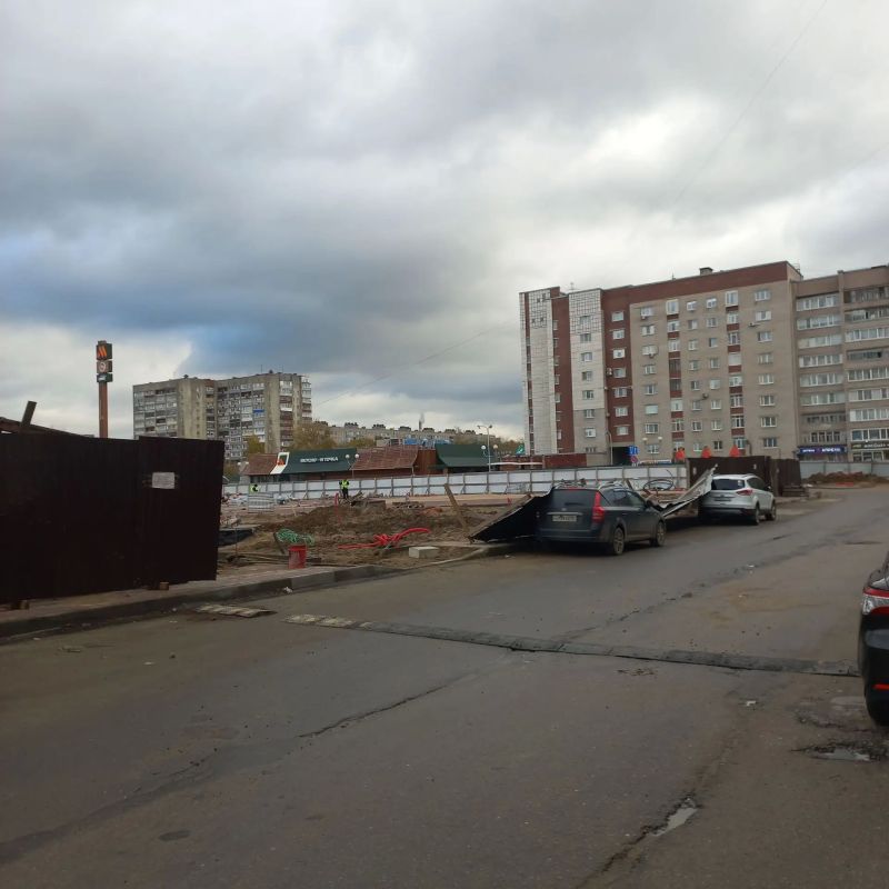 Забор на площади Химиков не выдержал напора ветра и прилег отдохнуть на припаркованные автомобили